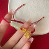 Gold tone Fu charm hanging from a red braided cord bracelet with pale green beads