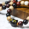 Close up of a wooden bead bracelet with a black cat charm and multi-colored wood beads