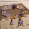 Close up of a lavender crystal bracelet with iridescent drop charms on a box