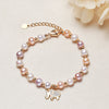 Close up view of a pearl bracelet with a gold elephant charm on a beige background