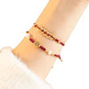 Close up of a wrist wearing two red string bracelets with gold tone charms