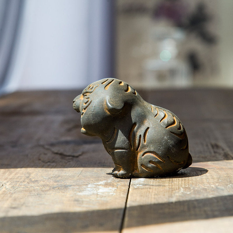Side view of a small rustic tiger statue sitting on a wooden table