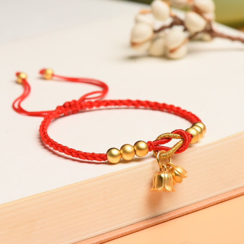 Red braided cord bracelet with gold beads and a lily of the valley charm
