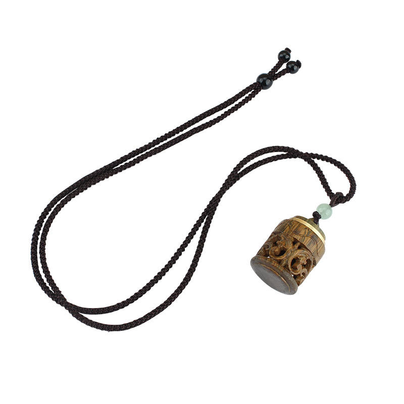 Carved green sandalwood cylinder pendant with gold-tone accents on a dark brown rope cord