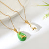 Green and white teardrop pendant necklaces with gold lotus accents on a white plate