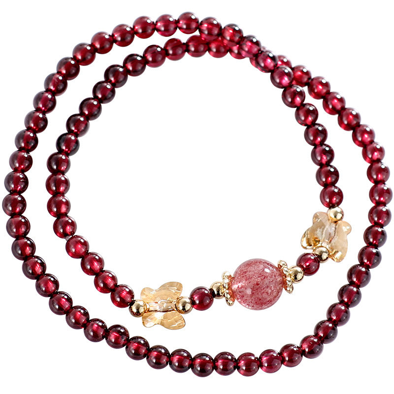Double wrap bracelet with red garnet beads, a pink stone, and gold butterfly charms on a white background