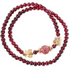 Double wrap bracelet with red garnet beads, a pink stone, and gold butterfly charms on a white background