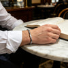 Silver tone hematite bracelet with rectangular beads on a wrist resting on a marble table