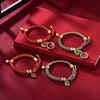 Two styles of braided Tibetan bracelets with gold charms on a red background