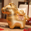 A golden plush horse doll sitting on a table with a decorative saddle