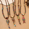 Long wooden bead necklace with colorful alloy pendant hanging against a beige background