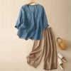 Flat lay of a blue embroidered V-neck top paired with beige wide-leg trousers
