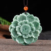 Close-up of a green carved jade lotus flower pendant on a dark cord