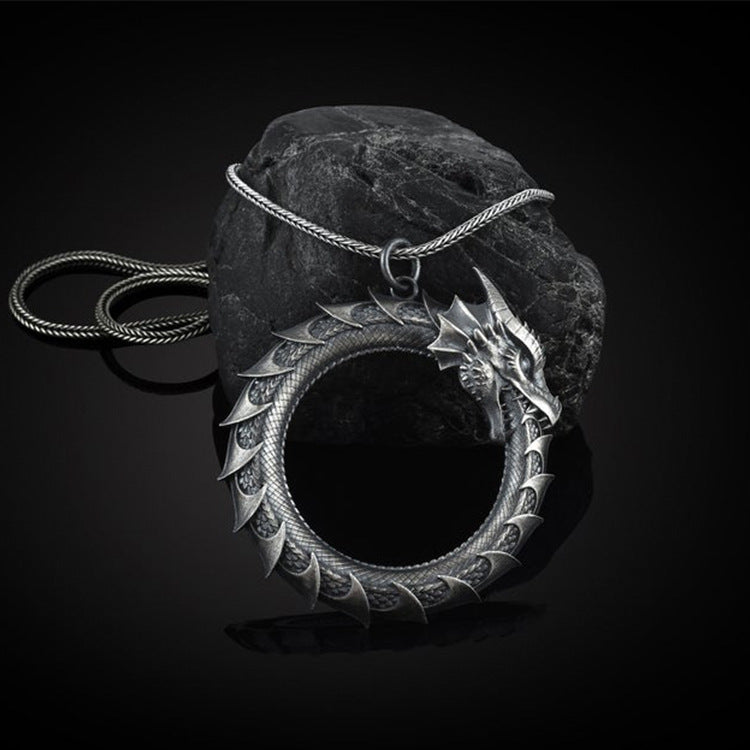 Silver-tone metal pendant shaped like a dragon eating its tail on a snake chain