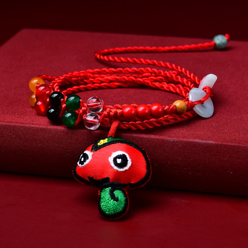 Close-up of a red woven waist chain with a small embroidered snake pendant and colorful beads on a red background.