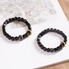 Dark square wood beads on a bracelet with a gold ring charm and a black and white Dzi bead
