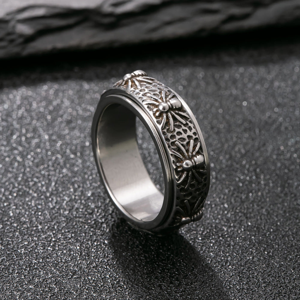 A silver-tone stainless steel ring with a rotating band featuring carved patterns.