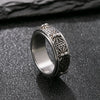 A silver-tone stainless steel ring with a rotating band featuring carved patterns.