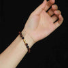 A wrist wearing a brown tiger eye bead bracelet with a small gold fish charm