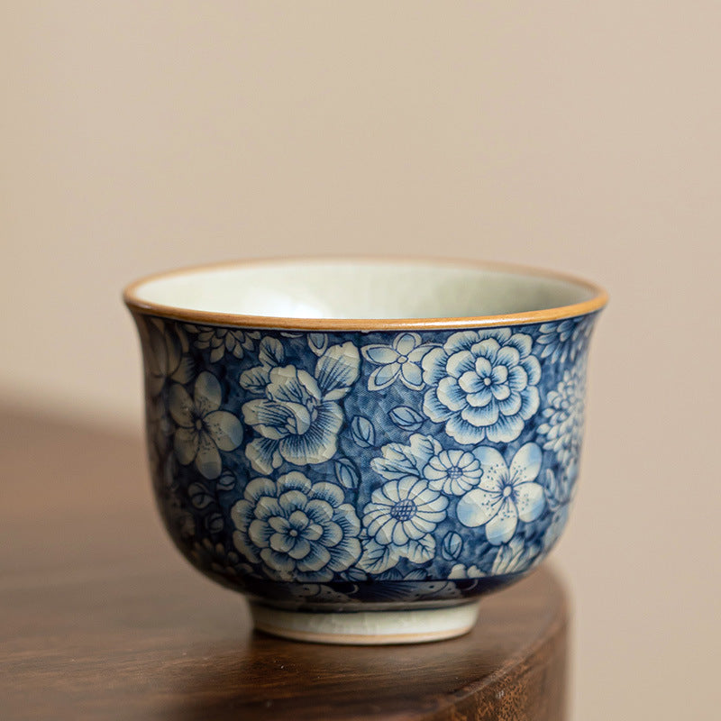 Hand holding a small blue and white ceramic teacup with a floral pattern