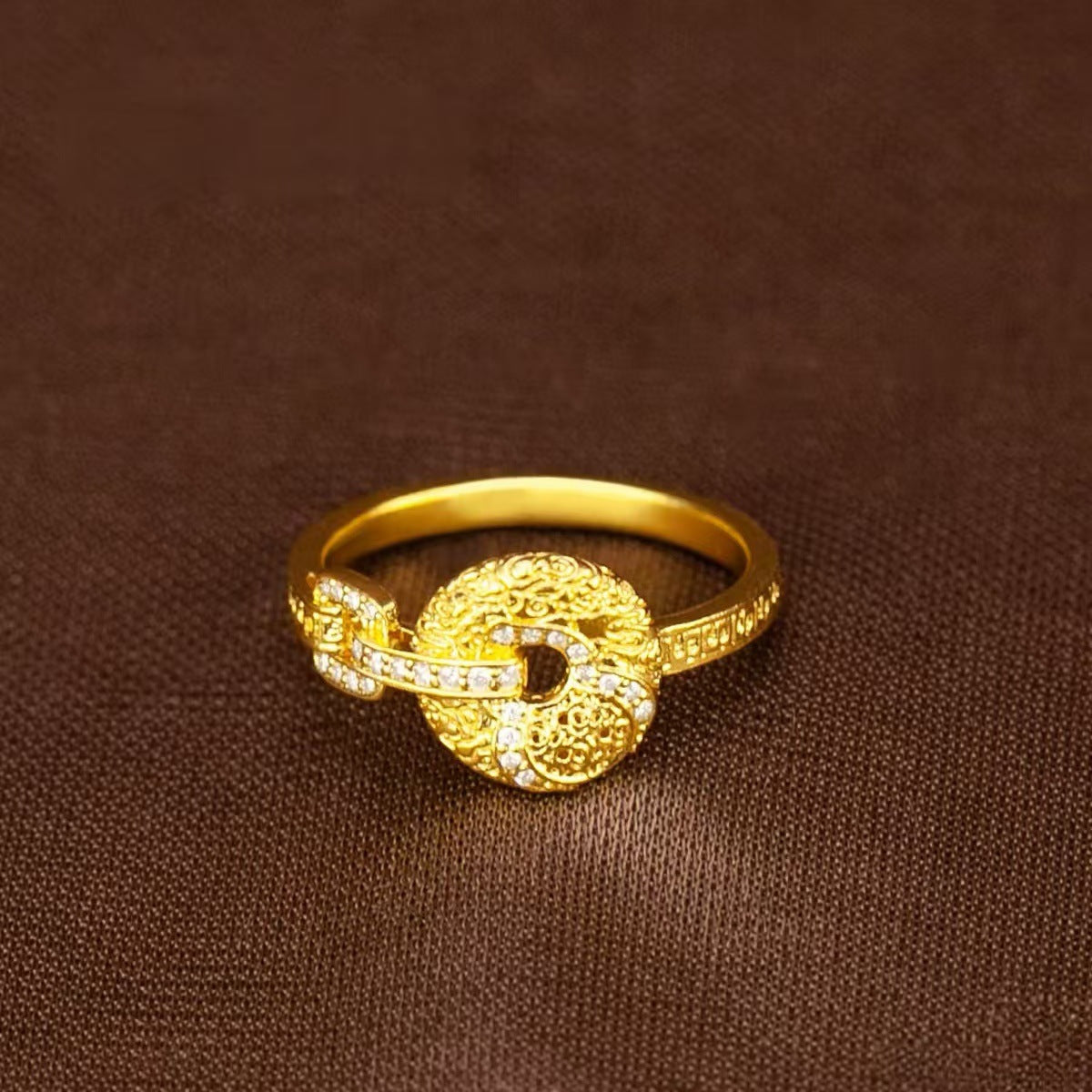 Close up of gold-tone adjustable ring with peace buckle and gourd charm