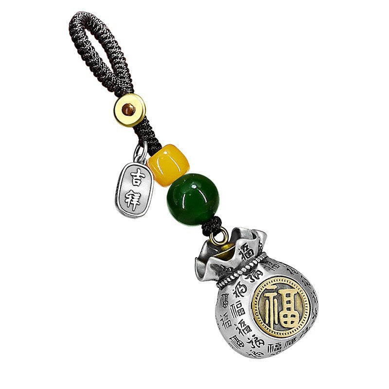 Close up of silver tone money bag keychain with green bead and gold Fu character