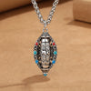 Close up of silver tone copper pendant with rotating mantra cylinder and koi design