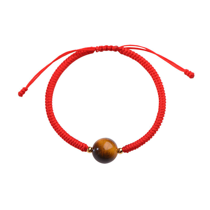 Close up of a red woven cord bracelet with a round tiger eye bead