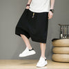 Man wearing black loose-fitting cotton linen harem shorts with white sneakers