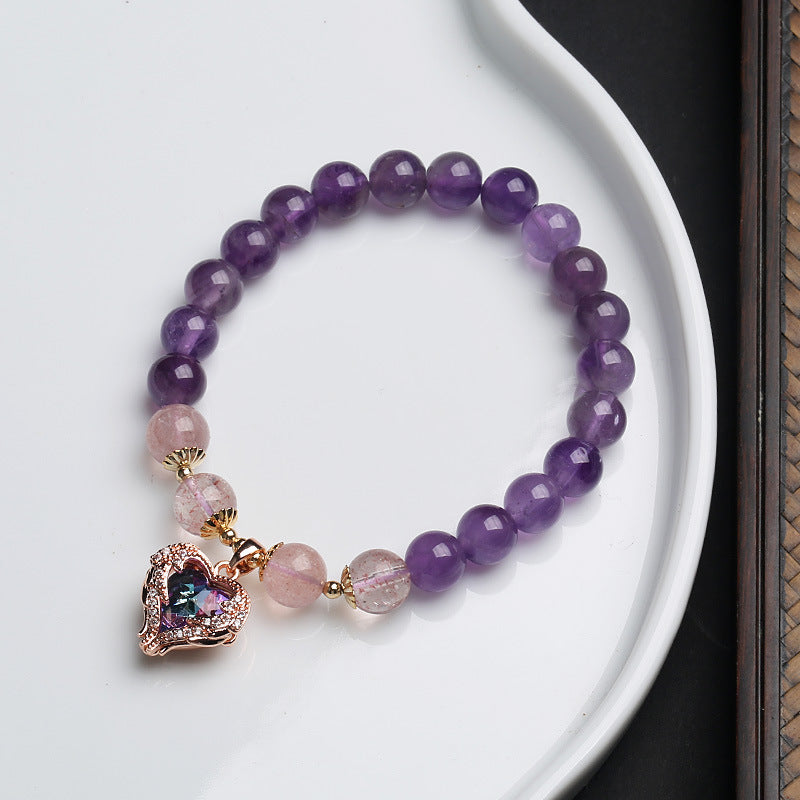Close-up of purple amethyst bracelet with pink quartz beads and a gold heart charm on a white dish