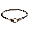 Close up of a black woven cord bracelet with a silver ring charm