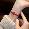 Close up of a red cord bracelet with a cinnabar peace buckle on a wrist