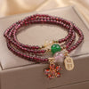 Close-up of a multi-strand red beaded bracelet with a gold flower charm