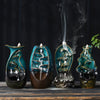 Four colorful ceramic waterfall backflow incense burners sitting on a wooden table