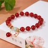 Red agate bracelet with jade bead and gold charm on a book