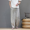 Front view of a man wearing loose grey harem pants with a plant pattern