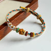 Close up of multi-colored braided bracelet with white and gold flower charms