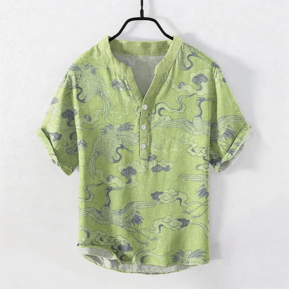 Light green short sleeve cotton henley shirt with grey crane and cloud pattern print hanging on a hanger