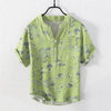 Light green short sleeve cotton henley shirt with grey crane and cloud pattern print hanging on a hanger