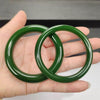 Two deep green glass bangles held in a hand showing their smooth texture