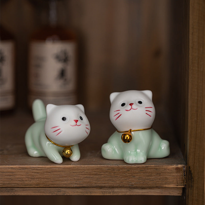Two mini ceramic lucky cat figurines sitting on a wooden shelf