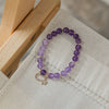 Amethyst crystal beaded bracelet with moon and star charm on a wooden stand