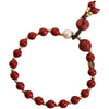 Red cinnabar bead bracelet with gold spacers, a carved clover charm, and a donut-shaped peace buckle pendant.