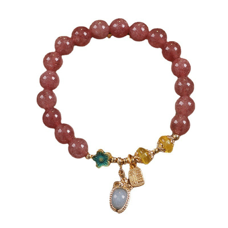 Close up of a pink beaded bracelet with gold charms on a white background