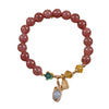Close up of a pink beaded bracelet with gold charms on a white background