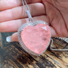 Close-up of a pink heart pendant with a silver-tone halo held in hand