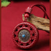 Red round cinnabar pendant with a rotating metal center on a cord