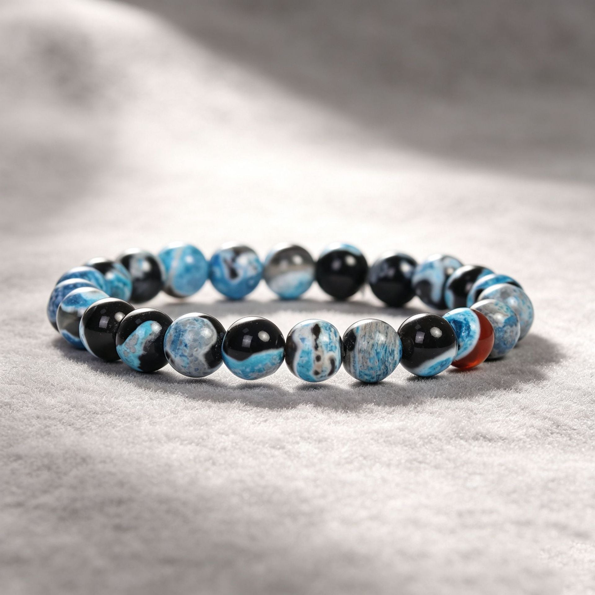 Close up of a blue and black beaded bracelet on a textured surface