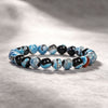 Close up of a blue and black beaded bracelet on a textured surface