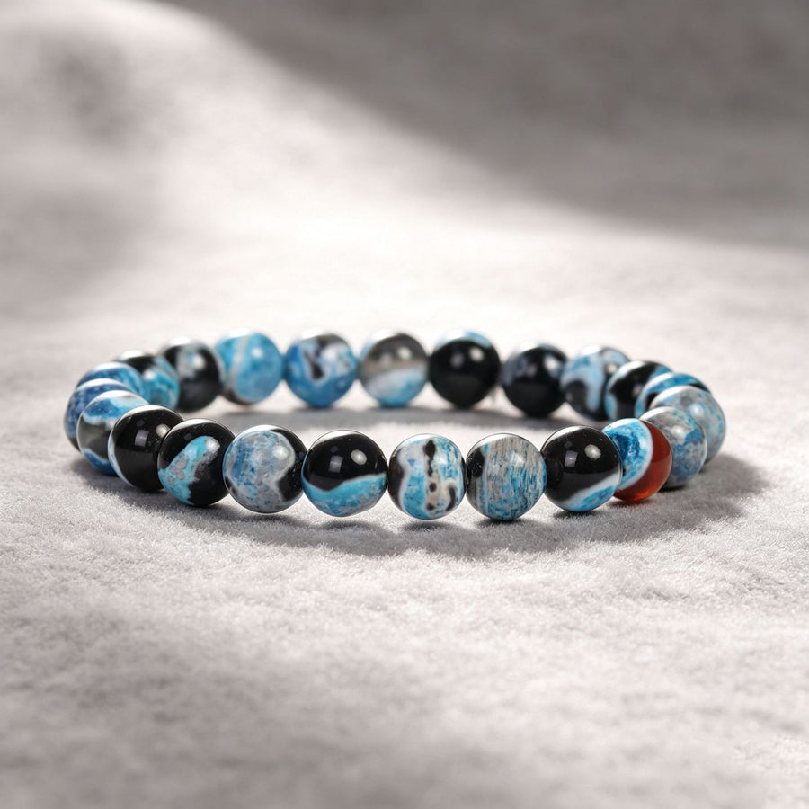 Close up of a blue and black beaded bracelet on a textured surface